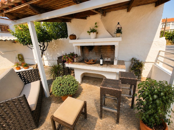 A patio with a fireplace, seating, and potted plants.