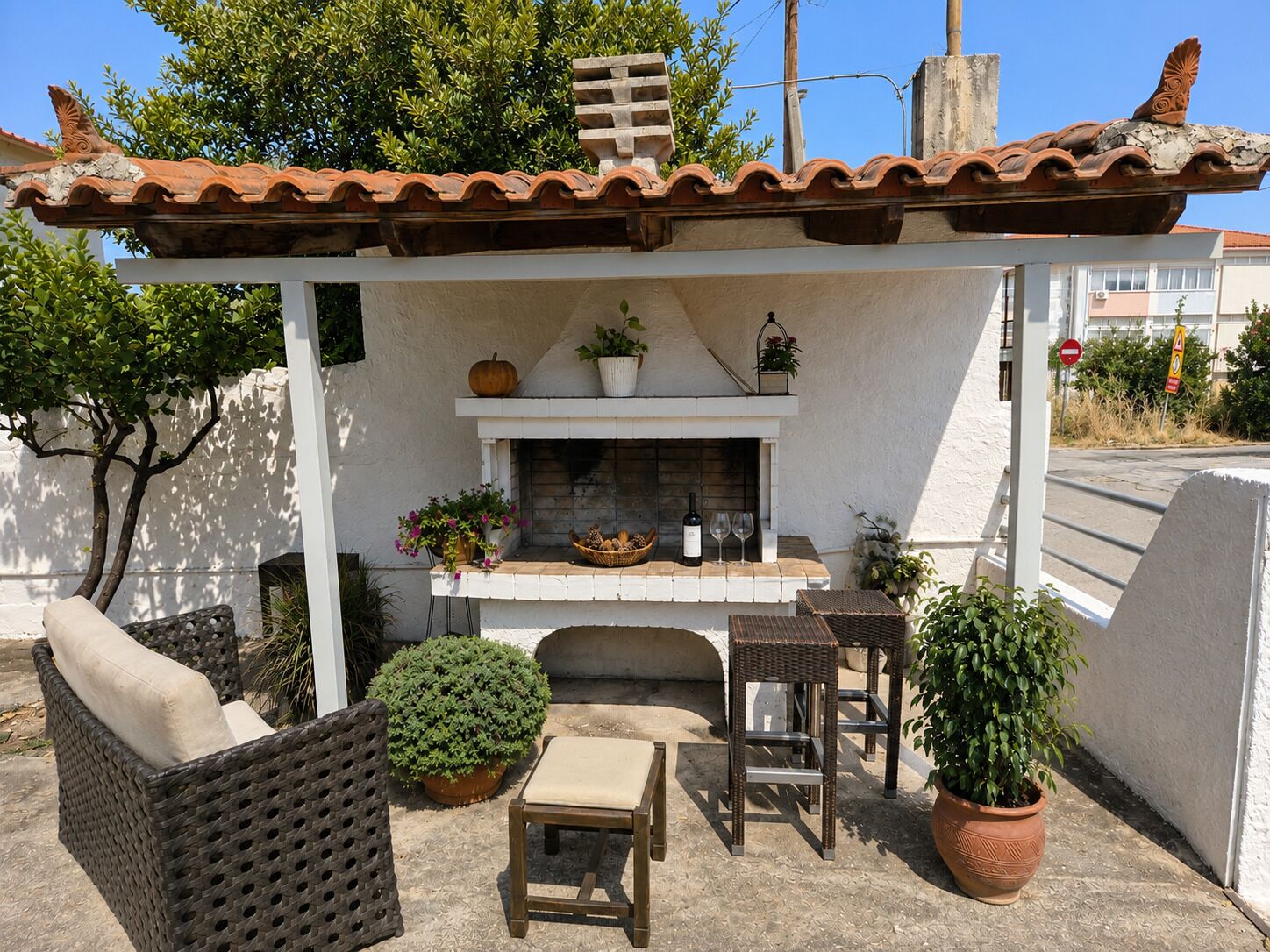 A patio with a fireplace, wicker furniture, and potted plants.