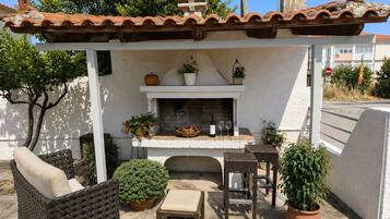 A patio with a fireplace, wicker furniture, and potted plants.