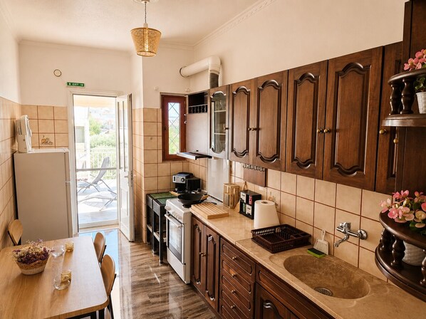 A kitchen with wooden cabinets, a sink, a stove, and a dining area with a table and chairs.
