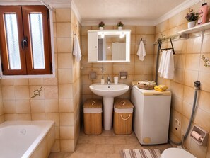A compact bathroom with a bathtub, a sink, and a toilet. There are two waste bins and a towel rack with towels. - Aposperitis - Endless View (Amarinthos)