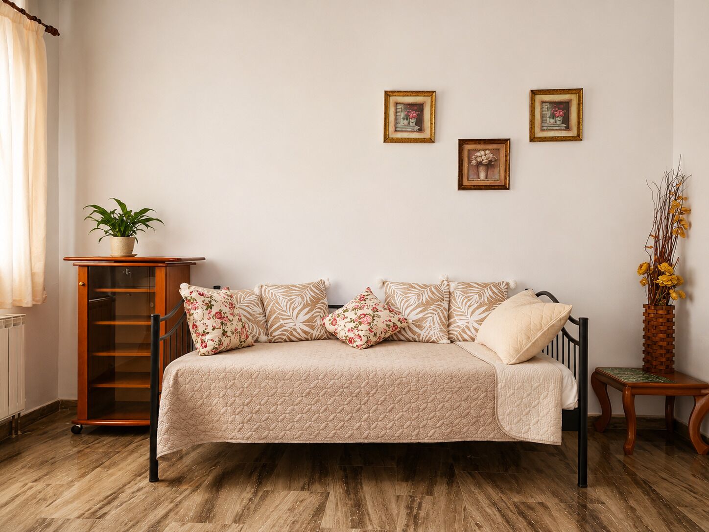 Ein Schlafzimmer mit einem Bett, einem Holzkabinett, einem Topfpflanzen und zwei gerahmten Bildern an der Wand.
