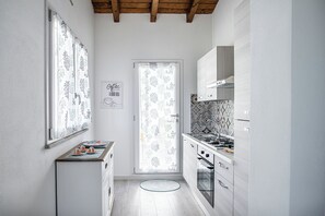 Eine moderne Küche mit weißen Schränken, einer gemusterten Spritzschutzwand und einem kleinen Essbereich mit einem runden Tisch.