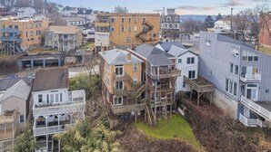 A residential area with multi-story buildings, including a house with a balcony and a staircase leading to a deck. - Skyline Luxury - Stylish 1BR with Panoramic Views (Pittsburgh)