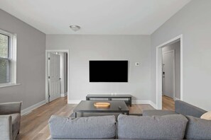 A modern living room with a flat-screen TV mounted on the wall, a grey sofa, and a coffee table with a tray.