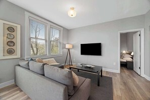 Een moderne woonkamer met een bank, een salontafel, een televisie en een lamp.