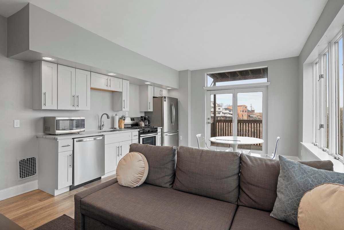 A modern apartment with a kitchenette, a sofa, and a balcony with a view.
