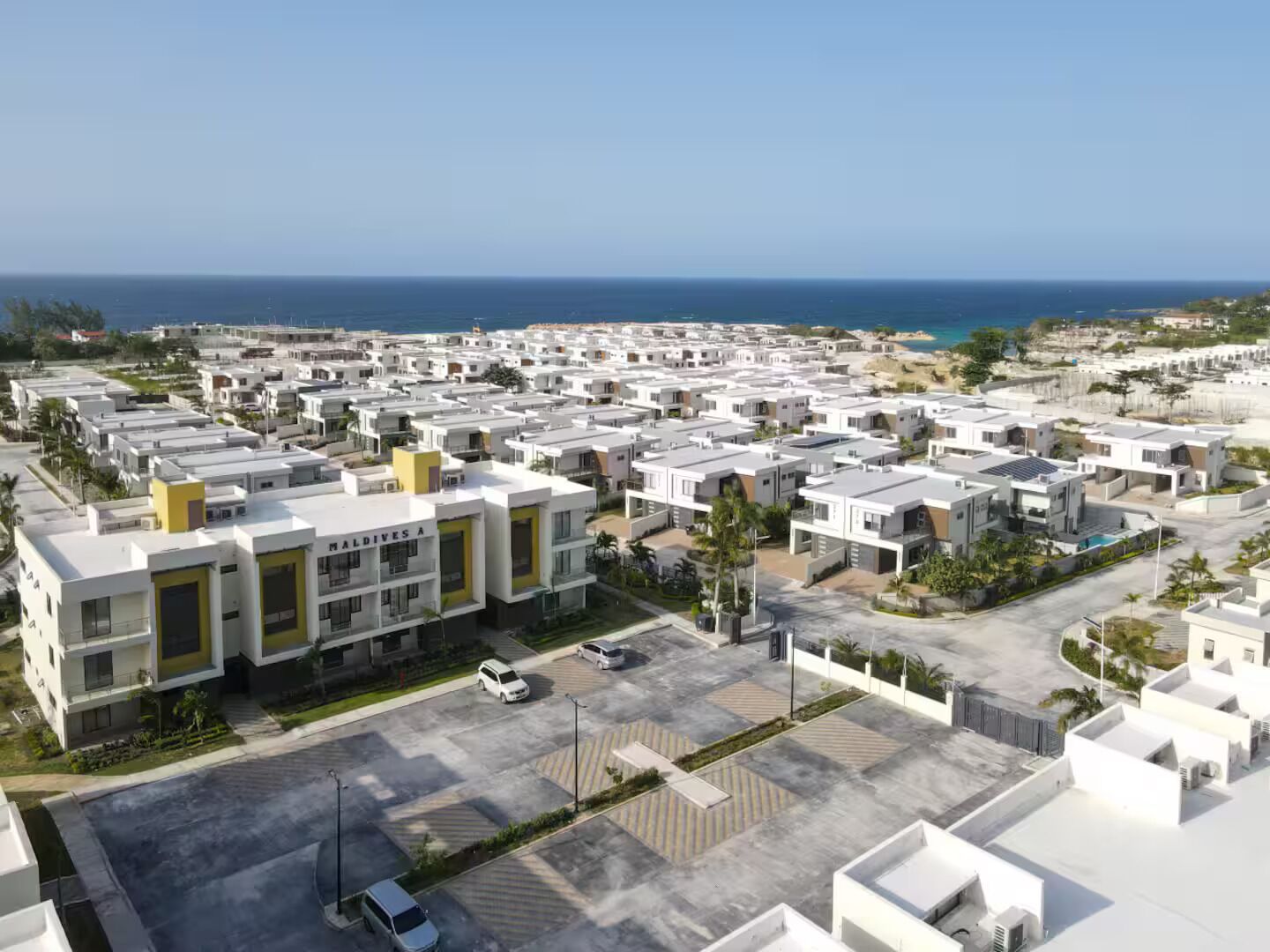 Un quartier résidentiel avec des immeubles d’appartements modernes, un parking et une vue sur l’océan.