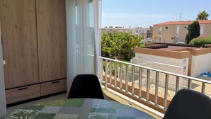 Un balcon offrant une vue sur les immeubles voisins et un ciel dégagé.