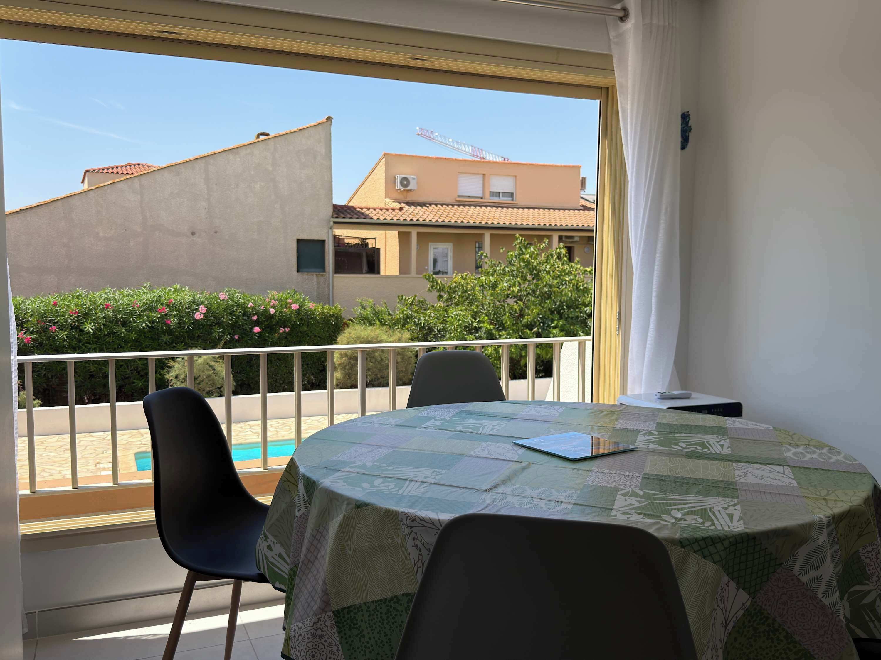 Ein Balkon mit Tisch, Stühlen und Blick auf Gebäude und Grünflächen.