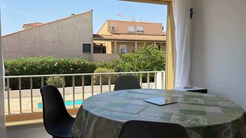 Ein Balkon mit Tisch, Stühlen und Blick auf Gebäude und Grünflächen.