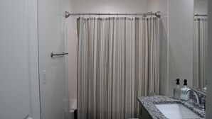 Une salle de bain avec un rideau de douche, un lavabo et un miroir.