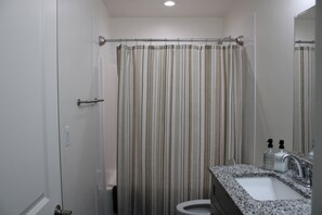 A bathroom with a shower curtain, a sink, and a mirror.