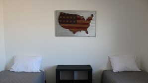 Une chambre avec deux lits, une table de chevet et une carte des États-Unis accrochée au mur.