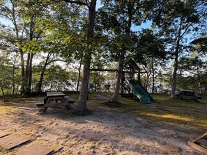 A park with picnic tables, a playground with a slide, and trees. - New listing, gorgeous home w/salt water pool in Sandwich, 
10 min from bridge!! (Sandwich)