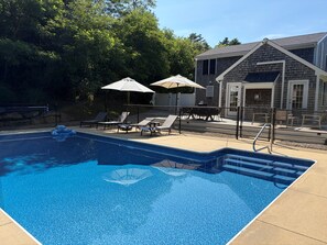 A swimming pool with lounge chairs and umbrellas, surrounded by a fence and trees. - New listing, gorgeous home w/salt water pool in Sandwich, 
10 min from bridge!! (Sandwich)