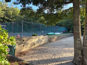 A fenced outdoor area with a gravel path, a wooden wall, and trees. - New listing, gorgeous home w/salt water pool in Sandwich, 
10 min from bridge!! (Sandwich)