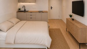 Una camera da letto con un letto, un comodino, una TV, un armadio e un angolo cottura.