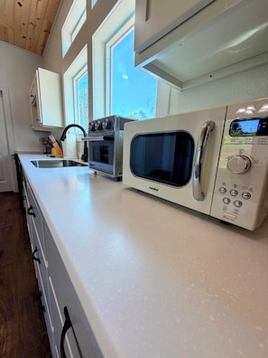 Una cocina con horno integrado, microondas y un amplio ventanal.