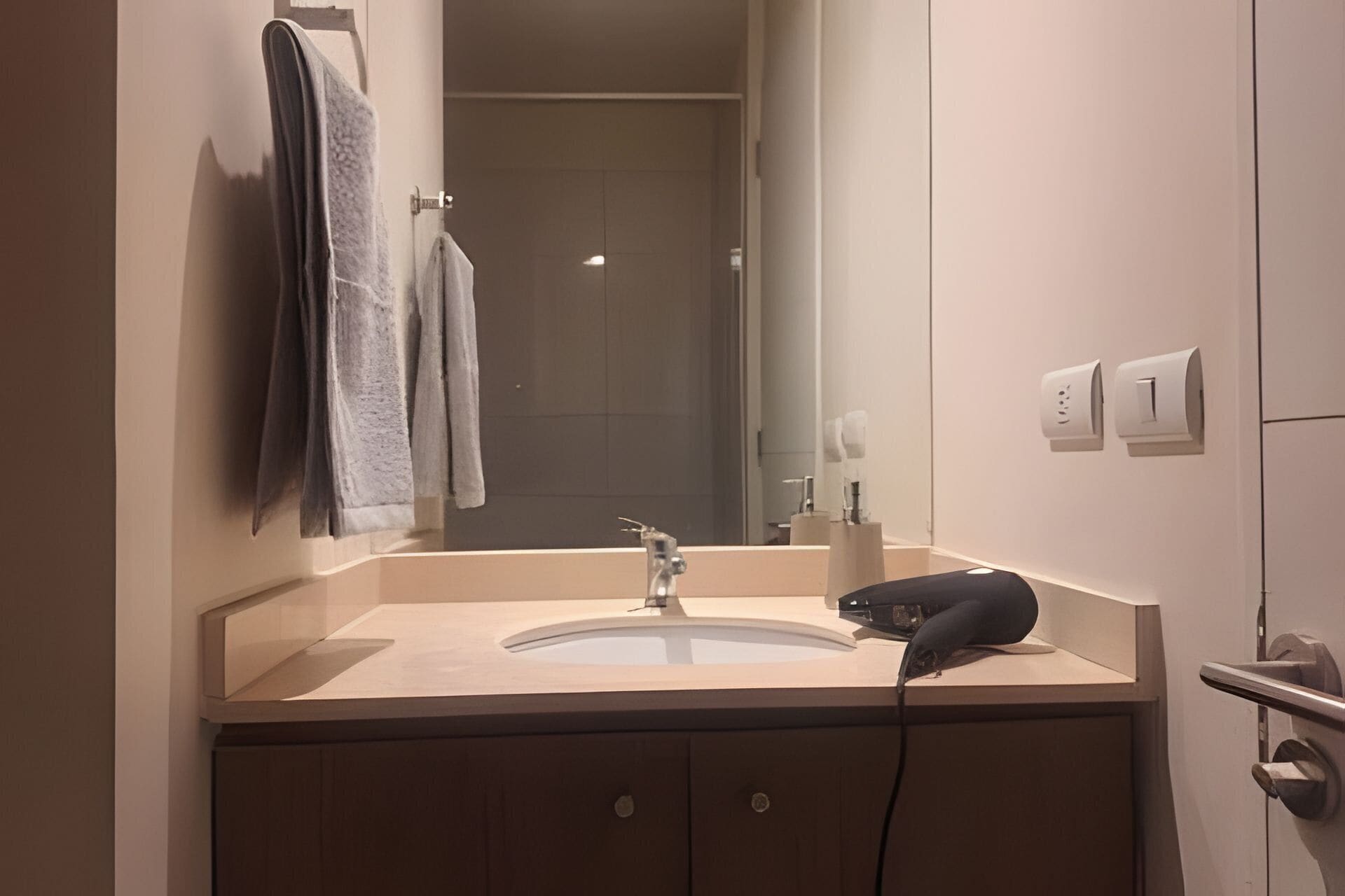A bathroom with a sink, mirror, towel rack, and a hairdryer.