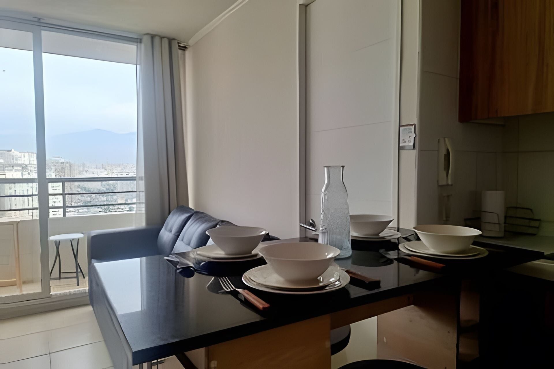 Een eethoek met een tafel voor vier personen, uitzicht op de stad en een keuken op de achtergrond.