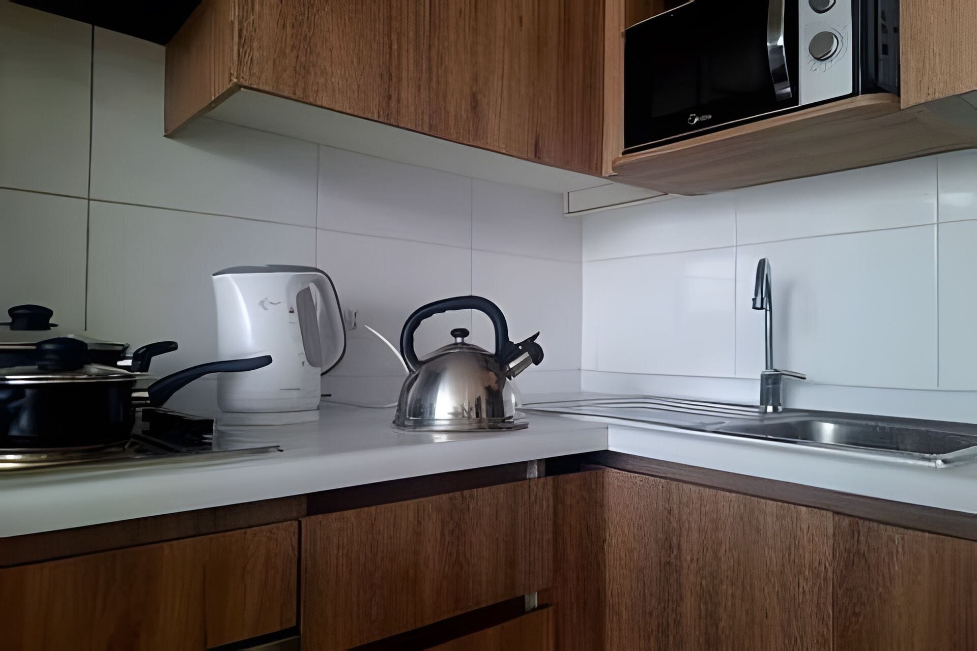 Une cuisine avec des meubles en bois, une bouilloire, une machine à café et un four à micro-ondes.