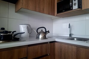 A kitchen with wooden cabinets, a kettle, a coffee maker, and a microwave.