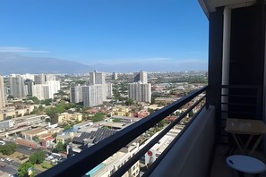 A balcony with a city view, including high-rise buildings and a mountain in the distance.