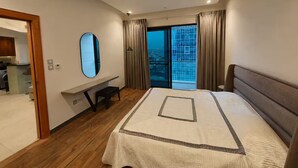 Ett modernt hotellrum med en stor säng, ett skrivbord, en spegel och utsikt över staden genom fönstret.