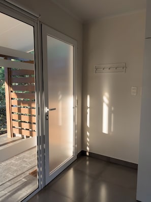 A room with a sliding glass door leading to an outdoor area with a wooden fence and greenery.