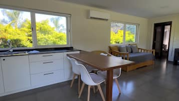 Eine moderne Küche mit weißen Schränken, einem Holztisch und einer Couch mit Kissen.