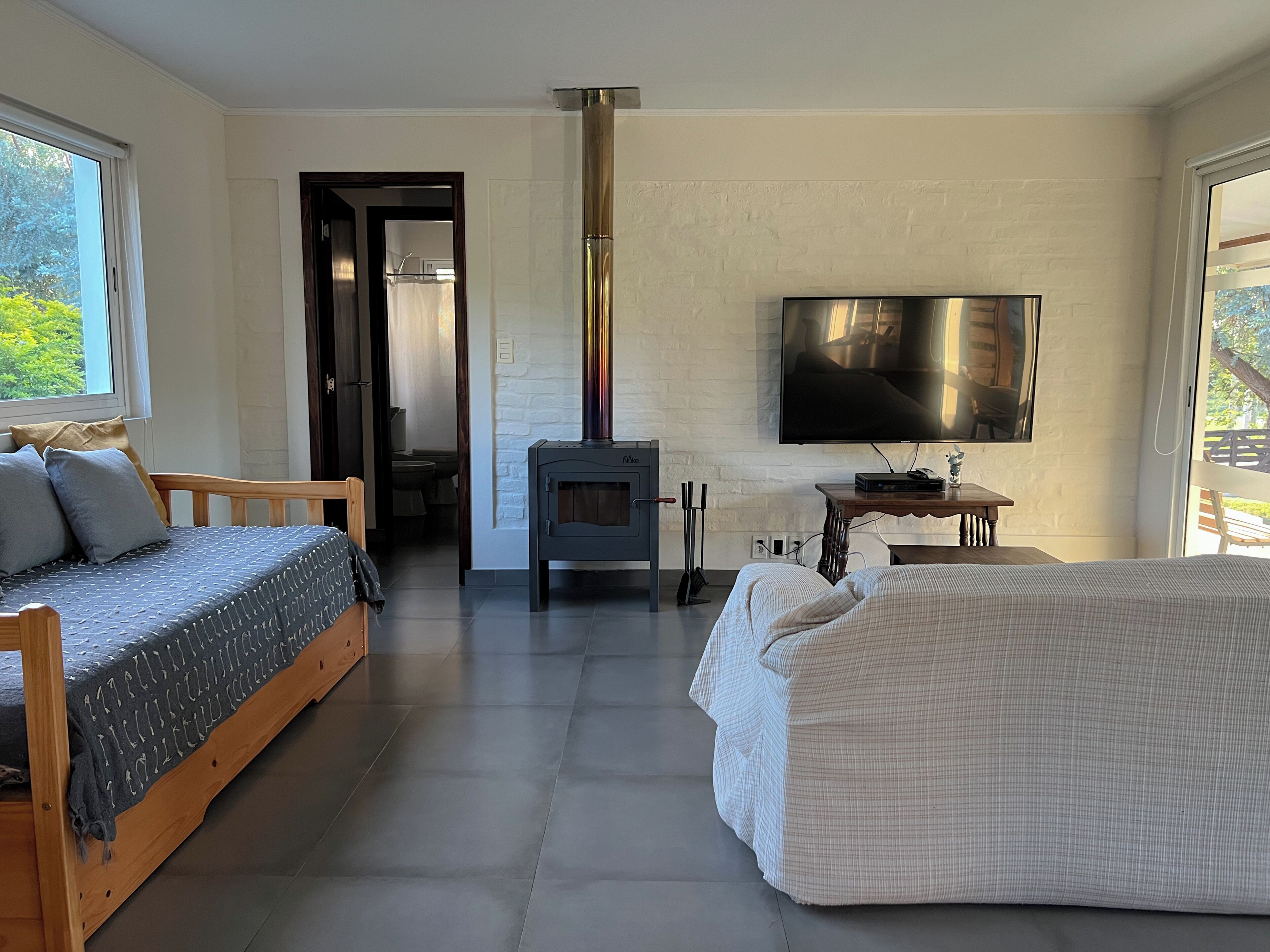 A modern room with a sofa, a bed, a fireplace, and a television.