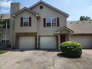 A two-story residential building with a garage, a chimney, and a well-maintained lawn.