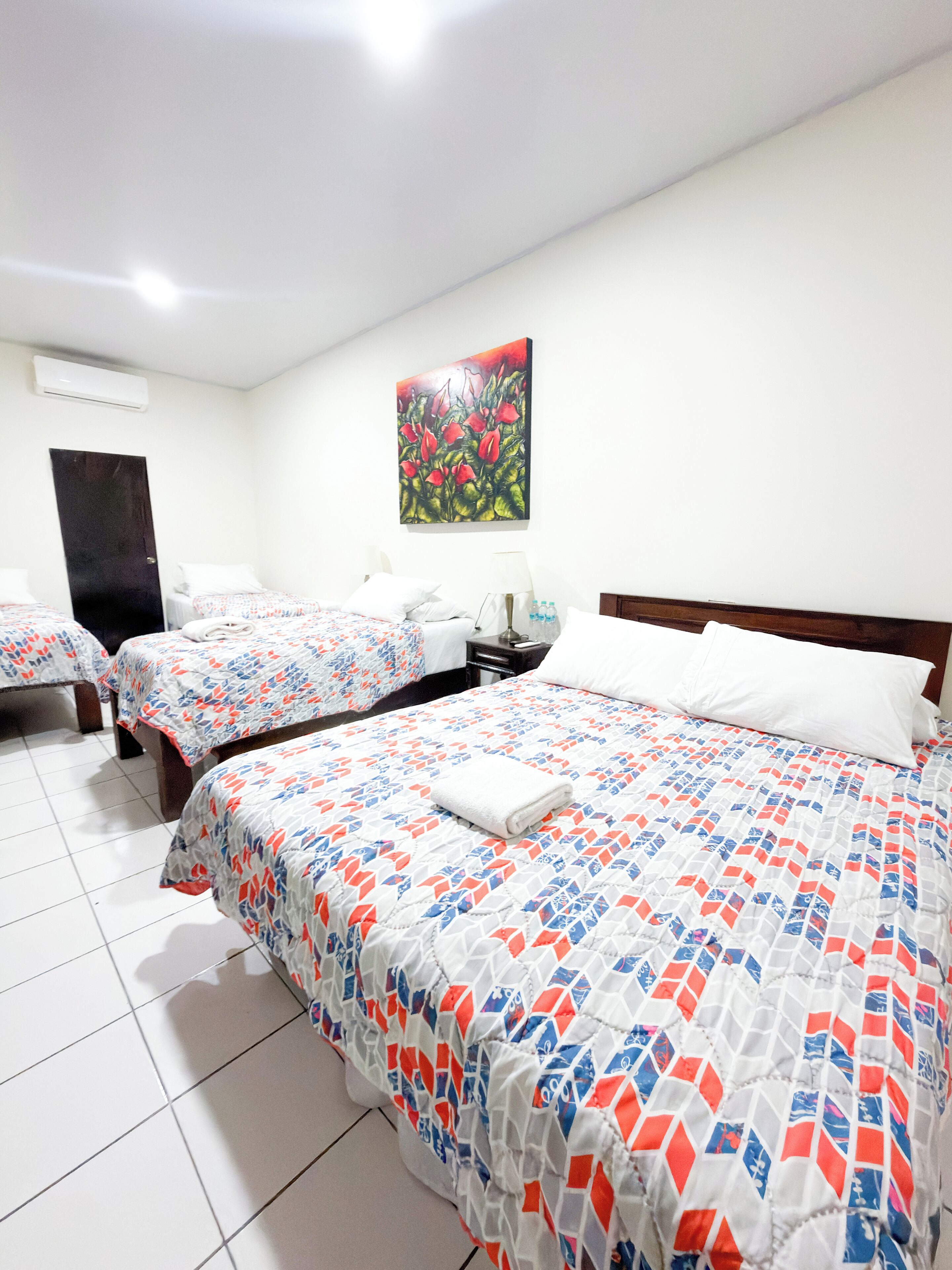 Een hotelkamer met twee bedden, een schilderij aan de muur en een nachtkastje met een lamp.