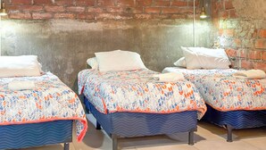 Een kamer met drie bedden, een bakstenen muur en een airconditioning.