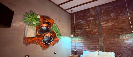 A bedroom with a bed, a brick wall, and a mural on the wall.