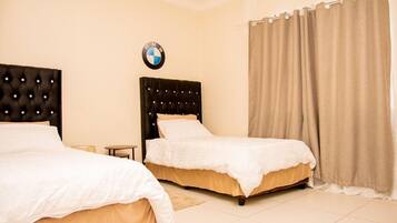 A hotel room with two beds, a BMW logo on the wall, and a curtain.