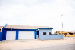 Um edifício térreo com fachada azul e telhado de telhas vermelhas.
