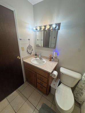A bathroom with a sink, mirror, toilet, and a towel rack. - Serene 3-bedroom house in Legendary Sturgis (Sturgis)