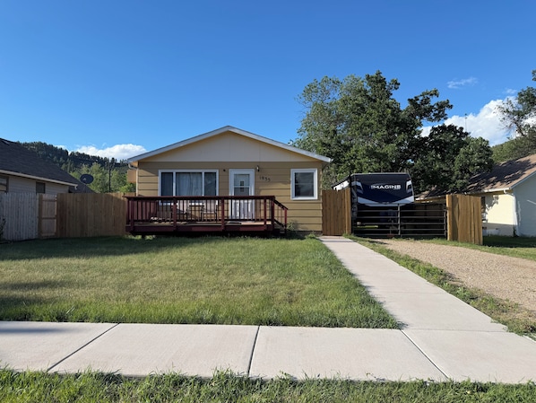A single-story house with a front deck, a gated driveway, and a satellite dish. - Serene 3-bedroom house in Legendary Sturgis (Sturgis)