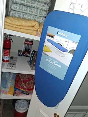 A closet with neatly folded bedding, a fire extinguisher, and an ironing board with a Whitmor advertisement. - King-Size Bed,1 or 2-Bedrooms, 1 bathroom, Walk to Beach-Quiet Neighborhood (Gulfport)