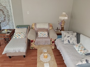 A cozy room with a bed, a sofa, and a chair, all with patterned bedding. There's a small table with a candle and a book. - King-Size Bed,1 or 2-Bedrooms, 1 bathroom, Walk to Beach-Quiet Neighborhood (Gulfport)