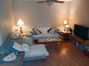 A living room with a sofa, a coffee table, a television, and a bookshelf. - King-Size Bed,1 or 2-Bedrooms, 1 bathroom, Walk to Beach-Quiet Neighborhood (Gulfport)