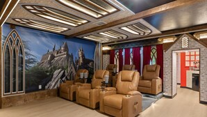 Ein Zimmer mit Wandgemälde eines Schlosses, Ledersessel, einer roten Tür und einer Steinwand.