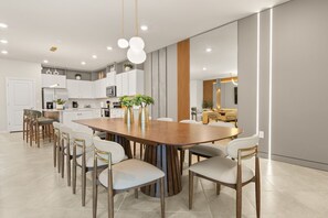 A modern kitchen with white cabinets, a wooden dining table, and a large window. - Spacious 22-Guest Retreat in Four Corners (Four Corners)