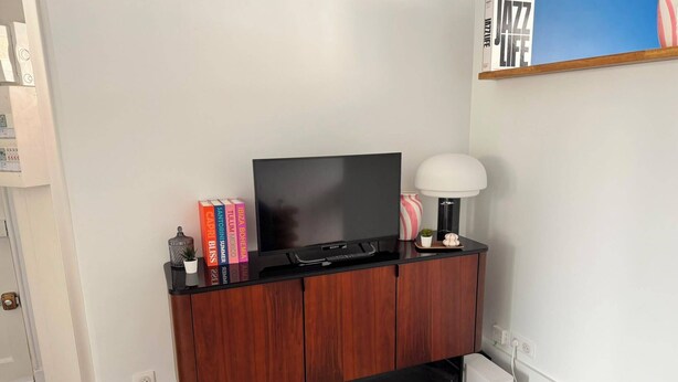 Eine schwarze Unterhaltungseinrichtung mit einem Flachbildfernseher, Büchern und Dekorationsobjekten.