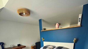 Ein Schlafzimmer mit kariertem Bettbezug, einem Schreibtisch mit Lampe und einer blauen Akzentwand.