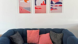 Ein blaues Sofa mit drei Kissen und drei gerahmten Kunstwerken an der Wand.