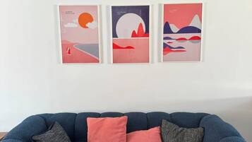 Un canapé bleu avec trois coussins et trois œuvres d’art encadrées accrochées au mur.