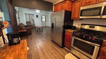 A kitchen with wooden cabinets, a stainless steel refrigerator, a stove, and a microwave.
